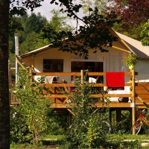 Hébergement insolite en Auvergne : tente lodge sur pilotis avec terrasse en bois.