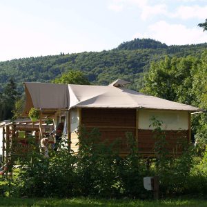 Cabane en bois à Auvergne, entourée de verdure et avec une vue sur les collines.