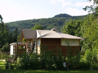 Cabane en bois à Auvergne, entourée de verdure et avec une vue sur les collines.