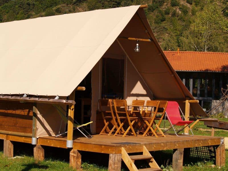 Tente safari en Auvergne, avec terrasse en bois et mobilier en extérieur.