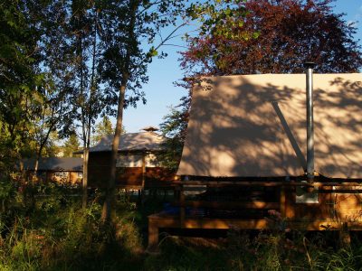 Tentes safari en bois, nichées dans la verdure dAuvergne, offrant un cadre paisible.