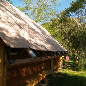 Tente en bois au cœur de la nature en Auvergne, entourée darbres verdoyants.