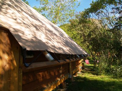 Tente en bois au cœur de la nature en Auvergne, entourée darbres verdoyants.