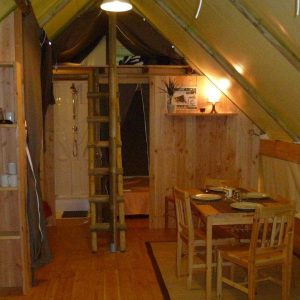 Hébergement insolite en Auvergne : cabane en bois avec cuisine et coin repas chaleureux.