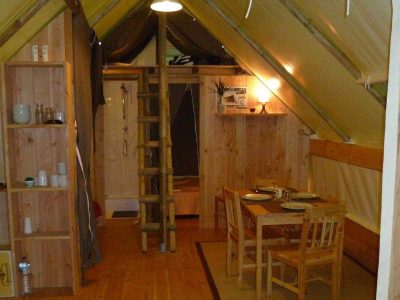 Hébergement insolite en Auvergne : cabane en bois avec cuisine et coin repas chaleureux.