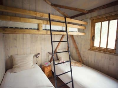 Chalet en bois avec lits superposés et fenêtre lumineuse, idéal pour un séjour en Auvergne.