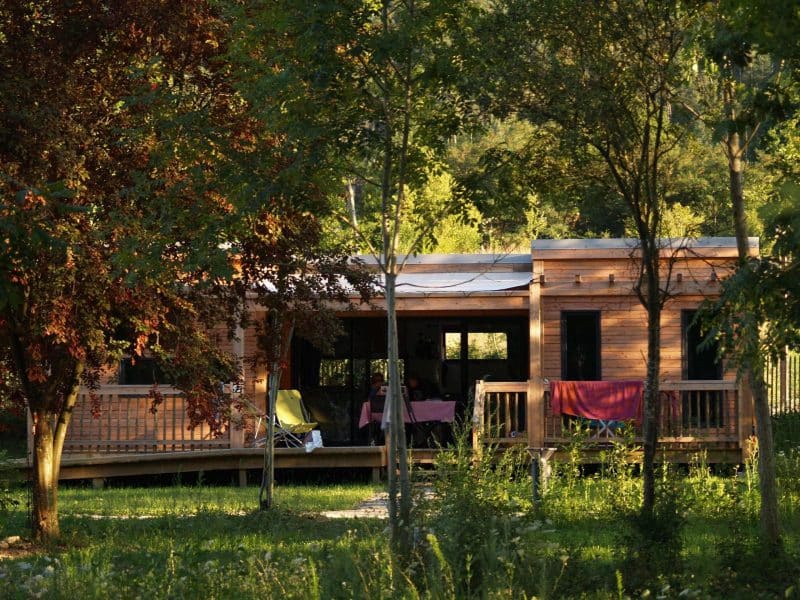 Cabane en bois au cœur de la nature, entourée darbres verdoyants.