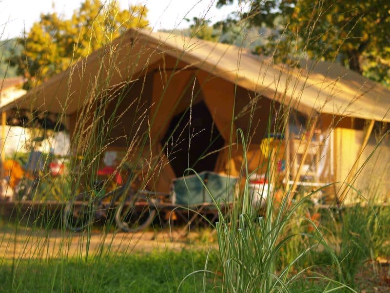 Tente safari en Auvergne, entourée de verdure et de lumière naturelle.