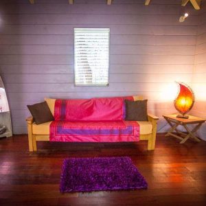 Hébergement insolite : un chalet coloré avec un canapé et une lampe design chaleureuse.