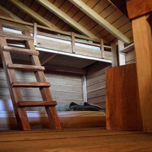 Cabane en bois avec mezzanine et échelle, ambiance chaleureuse et naturelle.