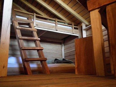 Cabane en bois avec mezzanine et échelle, ambiance chaleureuse et naturelle.