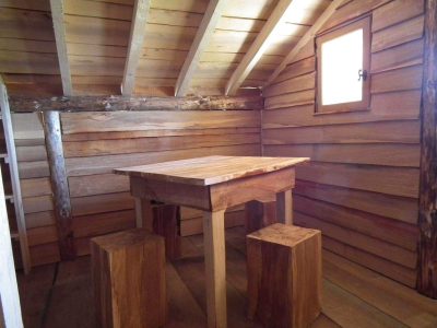 Cabane en bois dans le Grand-Est, avec une table en bois massif et des bancs rustiques.