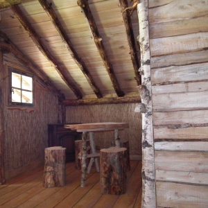 Cabane en bois dans le Grand-Est, avec une table en troncs et des murs en bois naturel.