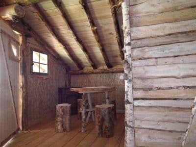 Cabane en bois dans le Grand-Est, avec une table en troncs et des murs en bois naturel.