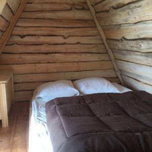 Cabane en bois dans le Grand-Est, avec un lit douillet et des murs en rondins.