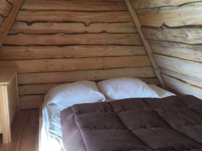Cabane en bois dans le Grand-Est, avec un lit douillet et des murs en rondins.