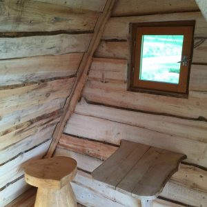 Cabane en bois dans le Grand-Est, avec un mobilier en bois naturel et une fenêtre lumineuse.