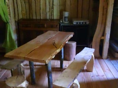 Cabane en bois dans le Grand-Est, avec une table en bois massif et des bancs rustiques.