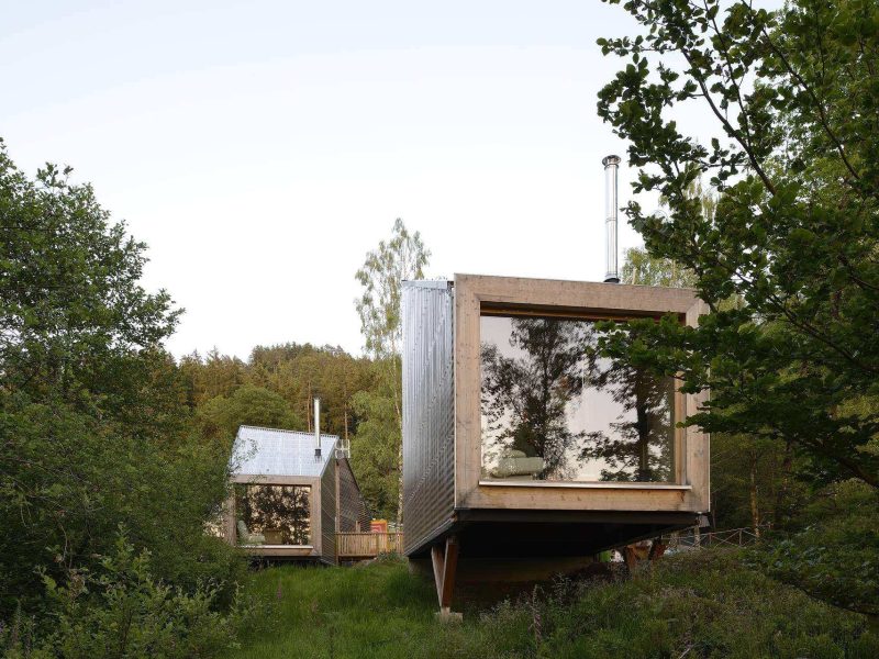 Cabines en bois modernes avec grandes fenêtres, nichées dans la verdure du Grand-Est.