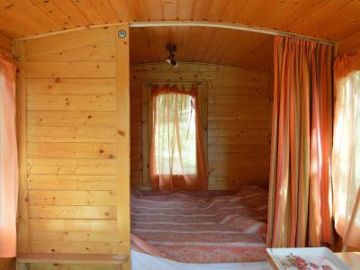 Intérieur chaleureux dune roulotte en bois, avec rideaux orange et lit douillet.