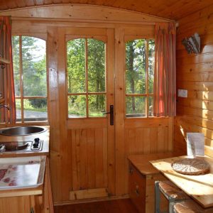 Intérieur chaleureux dune cabane en bois, avec cuisine et grandes fenêtres.