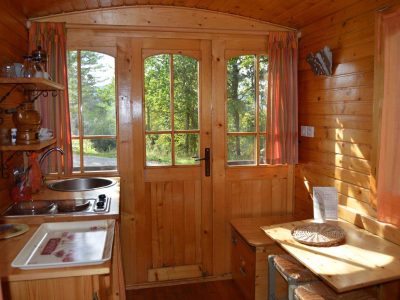 Intérieur chaleureux dune cabane en bois, avec cuisine et grandes fenêtres.