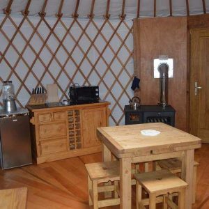 Yourte spacieuse à Grand-Est, avec un intérieur en bois chaleureux et un coin cuisine.