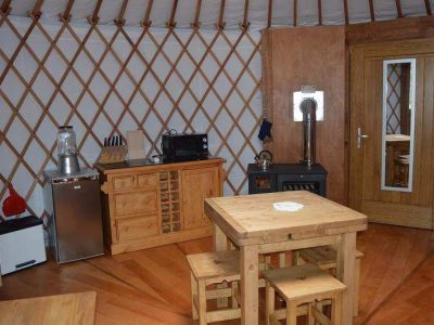 Yourte spacieuse à Grand-Est, avec un intérieur en bois chaleureux et un coin cuisine.