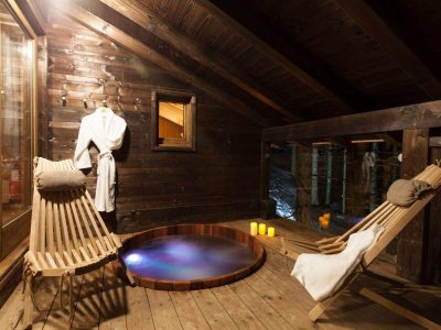 Hébergement insolite en Auvergne-Rhône-Alpes avec un jacuzzi et des fauteuils en bois.