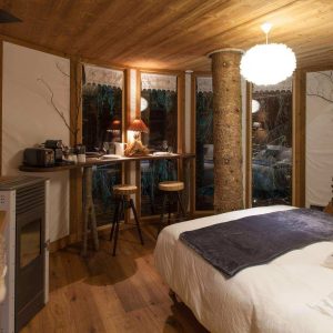 Chalet en bois chaleureux avec lit douillet et vue sur la nature environnante.