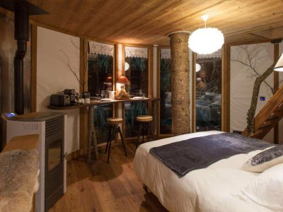 Chalet en bois chaleureux avec lit douillet et vue sur la nature environnante.