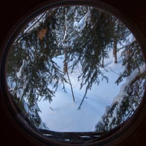 Vue depuis un hébergement insolite en bois, entouré de neige et darbres.