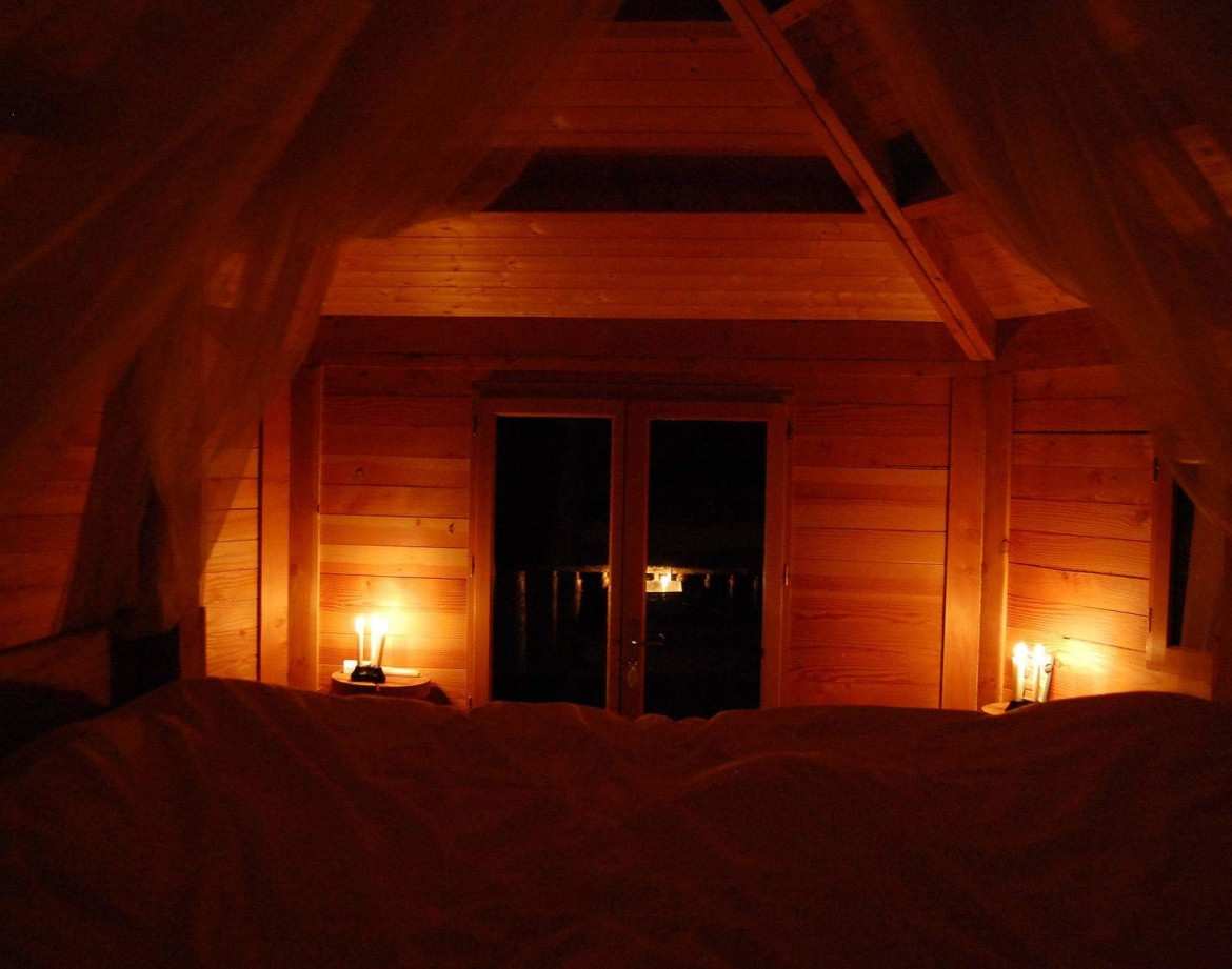 Cabane en bois cosy avec lumière tamisée et vue sur la nature. Parfait pour un séjour romantique.
