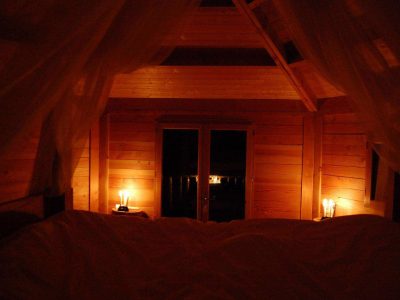 Cabane en bois cosy avec lumière tamisée et vue sur la nature. Parfait pour un séjour romantique.