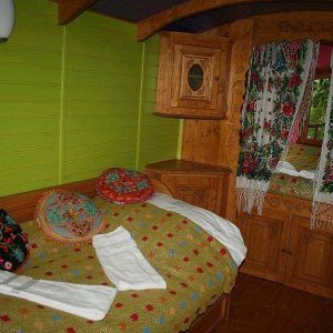 Chalet en bois coloré avec des coussins fleuris et des rideaux brodés.