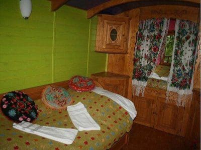 Chalet en bois coloré avec des coussins fleuris et des rideaux brodés.
