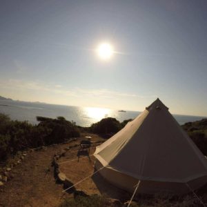 Tente de glamping avec vue sur la mer et le soleil levant. Ambiance paisible et naturelle.