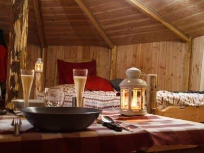 Hébergement insolite en Auvergne : cabane en bois avec lit douillet et lanternes chaleureuses.