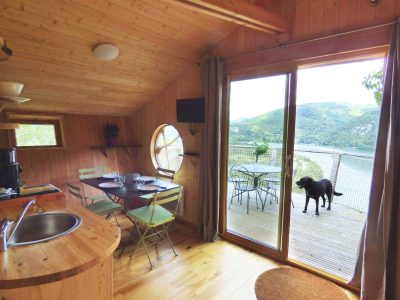 Cabane en bois avec vue sur le lac et terrasse, idéale pour un séjour nature.