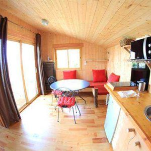 Cabane en bois cosy avec cuisine équipée et vue sur la nature.