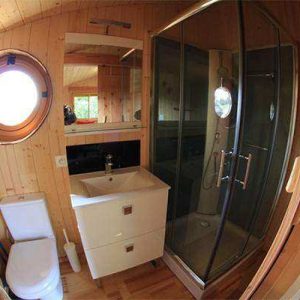 Cabane en bois avec salle de bain moderne et fenêtre ronde, au cœur de lAuvergne.