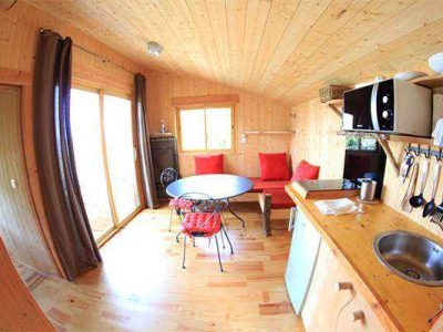Cabane en bois chaleureuse avec cuisine équipée et vue sur la nature.