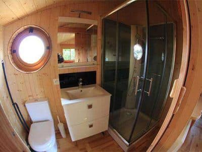 Cabane en bois avec salle de bain moderne et fenêtre ronde, au cœur de lAuvergne.