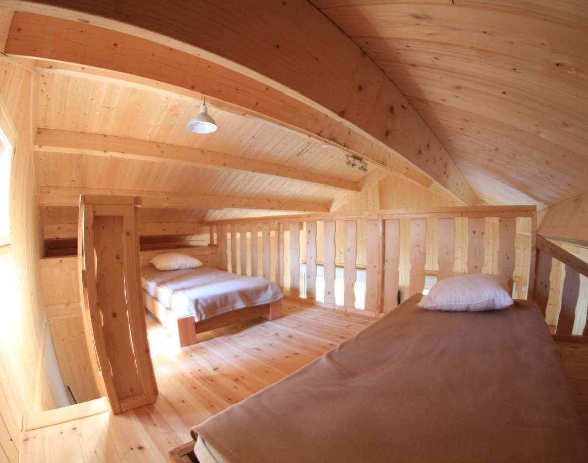 Cabane en bois dans les combles, avec lits simples et ambiance chaleureuse.