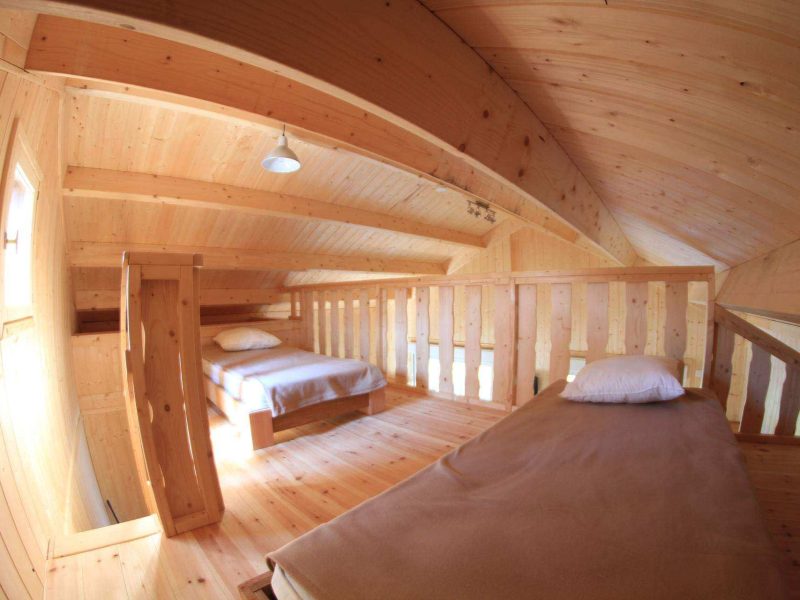 Cabane en bois dans les combles, avec lits simples et ambiance chaleureuse.