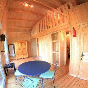 Cabane en bois chaleureuse avec mezzanine et coin repas convivial.