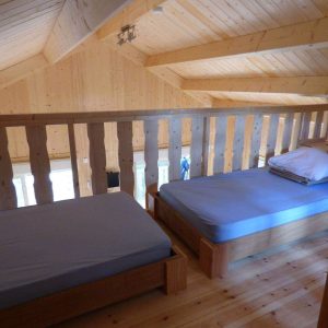 Chalet en bois avec lits simples, ambiance chaleureuse et lumineuse en Auvergne-Rhône-Alpes.
