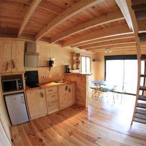 Cabane en bois chaleureuse avec cuisine équipée et vue sur la nature.