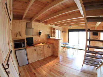Cabane en bois chaleureuse avec cuisine équipée et vue sur la nature.