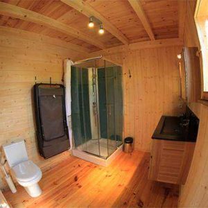 Cabane en bois avec salle de bain moderne et éclairage chaleureux.
